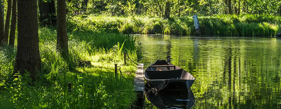 Boot an einem Steg Wasserkanal mit altem Boot im Biosphärenreservat Spreewald im Bundesland Brandenburg, Deutschland, im Frühjahr.